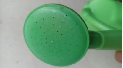 Green watering can with a close-up of the nozzle.